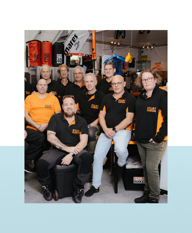 Groep medewerkers poseert samen in een duikwinkel.